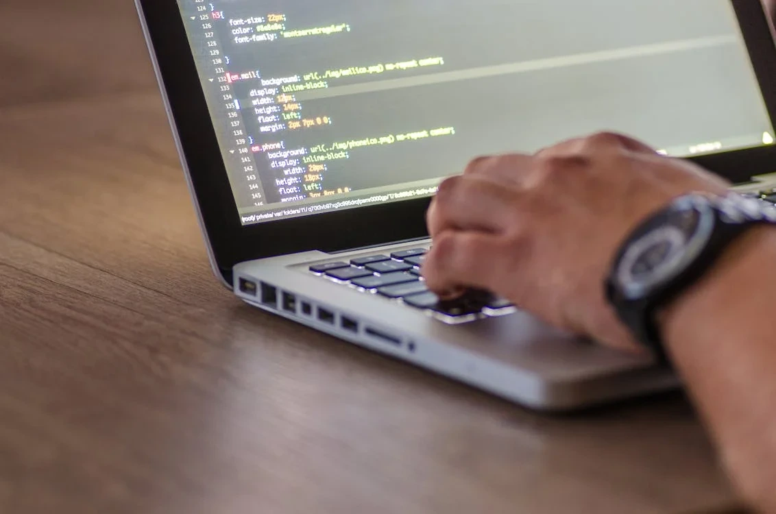 A laptop on a wooden table with some coding